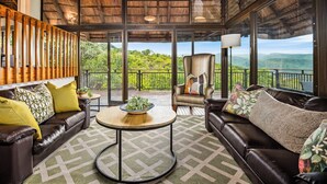 A spacious room with a high ceiling, large windows, and a view of lush greenery. - Jozini Tiger Lodge by Dream Resorts (Jozini)