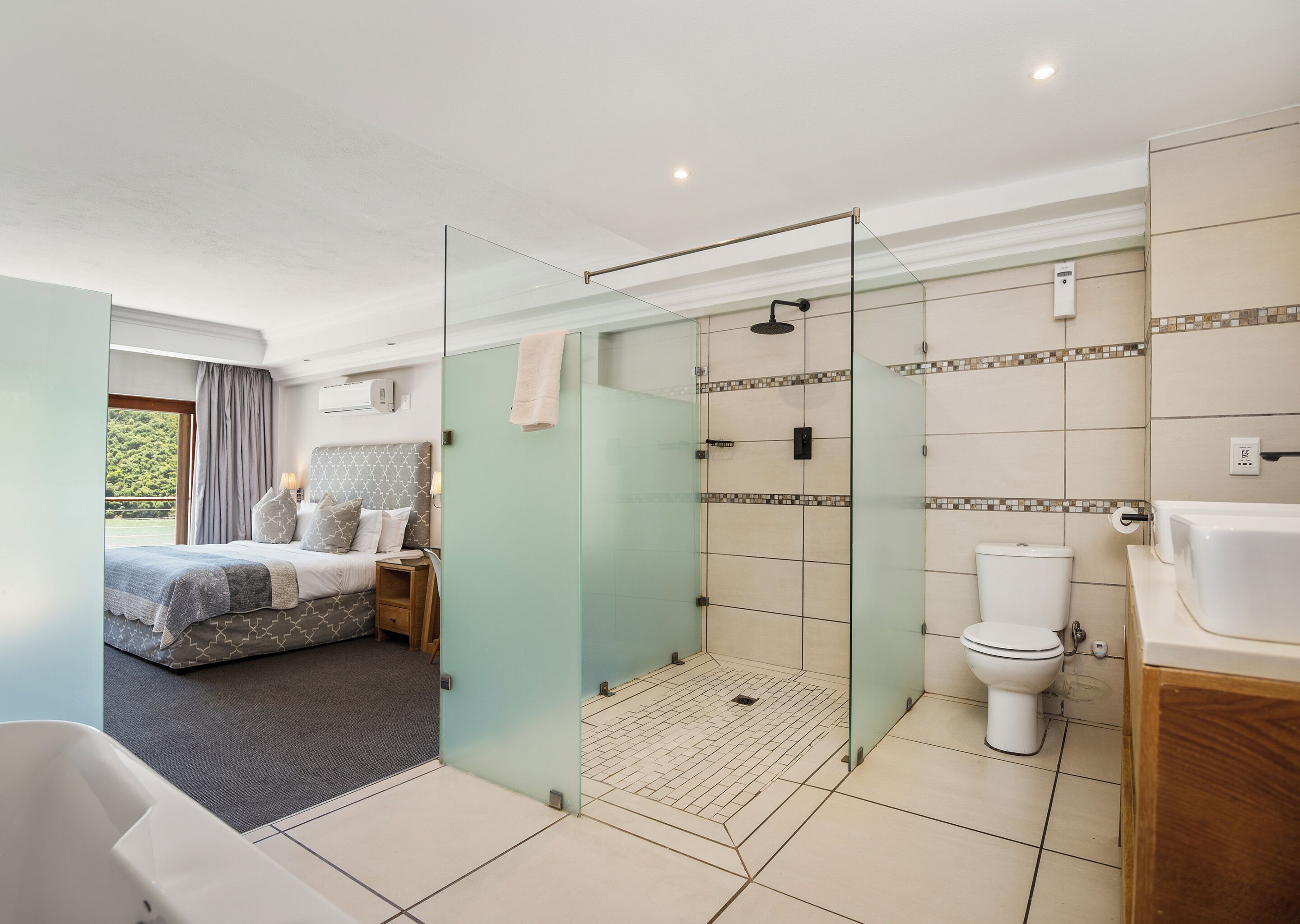 A modern bathroom with a glass-enclosed shower, a toilet, and a bathtub.