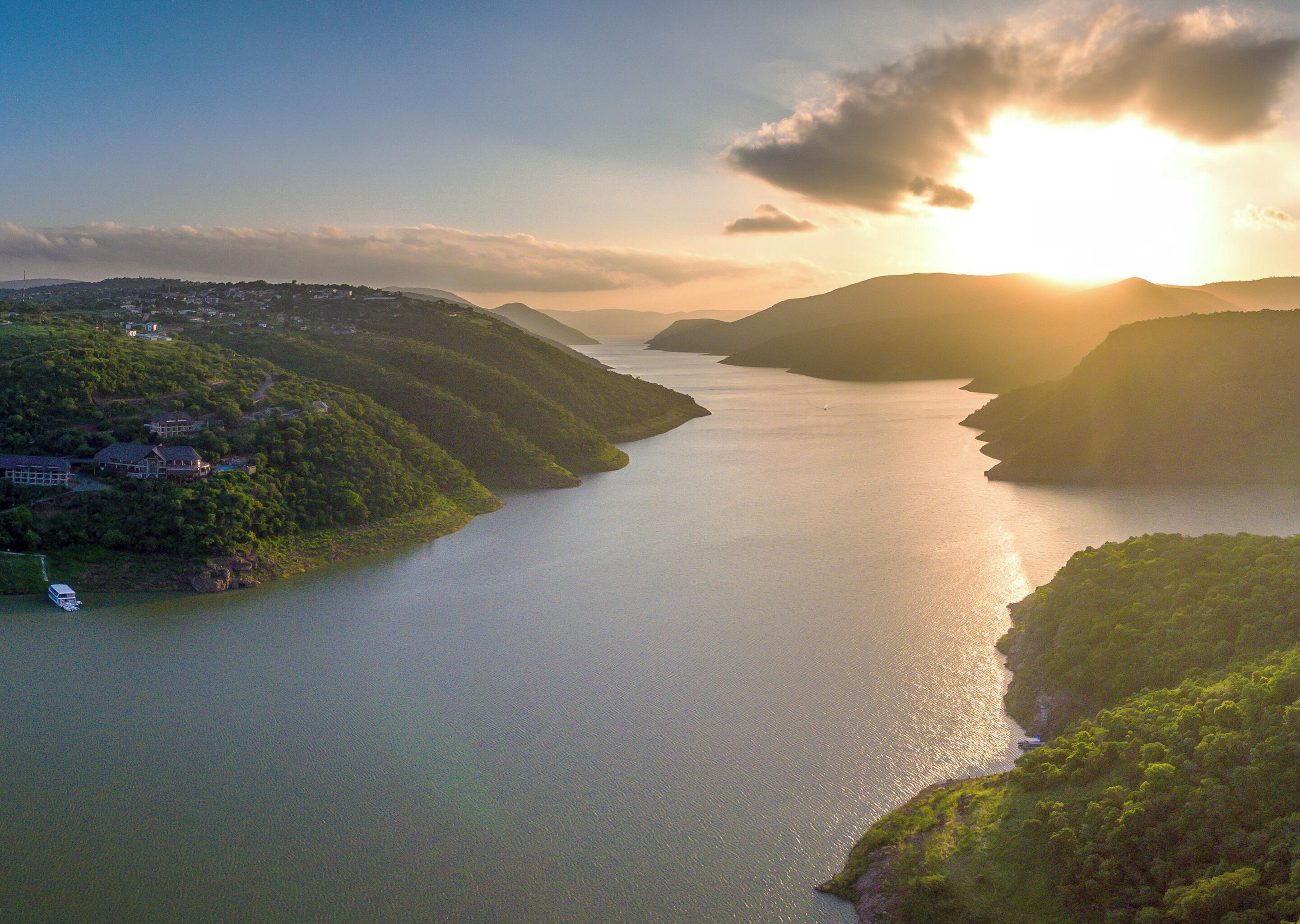 A coastal landscape with a body of water, hills, and a few buildings.