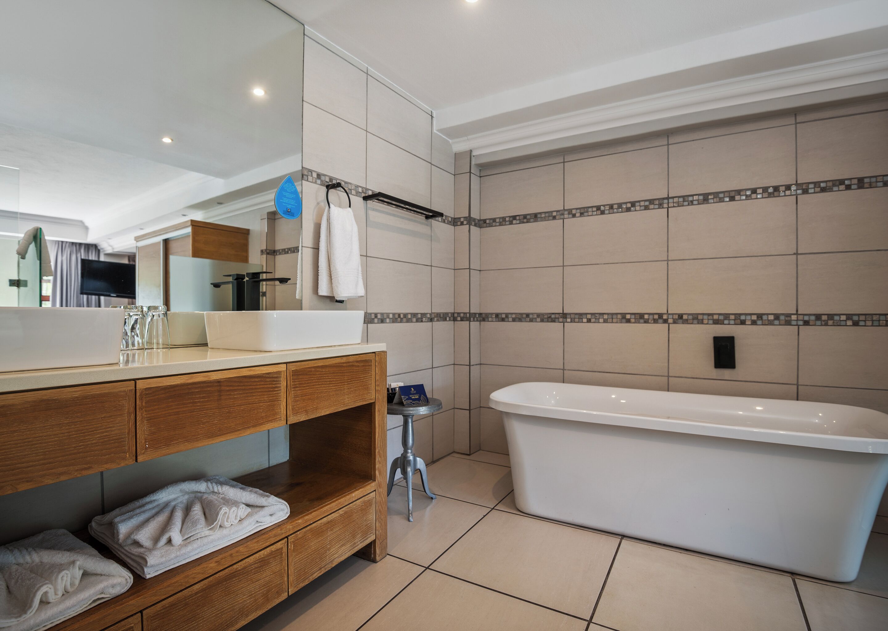 Une salle de bain moderne avec une grande baignoire, un meuble-lavabo en bois et des murs carrelés.
