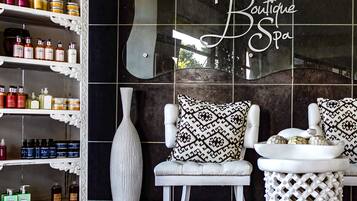 Experience tranquility in this serene spa setting, featuring a large mirror, plush chair, and elegant side table.