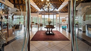 A spacious lobby with a high ceiling, a chandelier, and a view of the outdoors. - Jozini Tiger Lodge by Dream Resorts (Jozini)