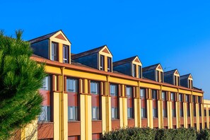 A row of yellow buildings with multiple windows and a flat roof. - Le Green des Impressionnistes – Cergy‑Pontoise (Ennery)