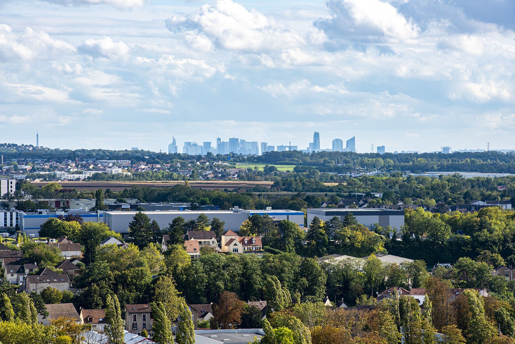 Un paysage urbain mêlant des immeubles résidentiels et commerciaux, une tour imposante et une silhouette urbaine caractérisée par de nombreux gratte-ciel.