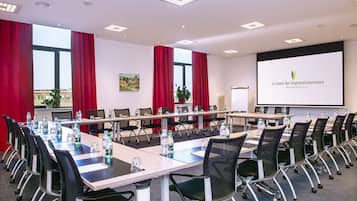 Un salón de conferencias con una larga mesa, sillas y una pantalla de proyector que muestra "Le Green des Impressionnistes RESIDENCE".