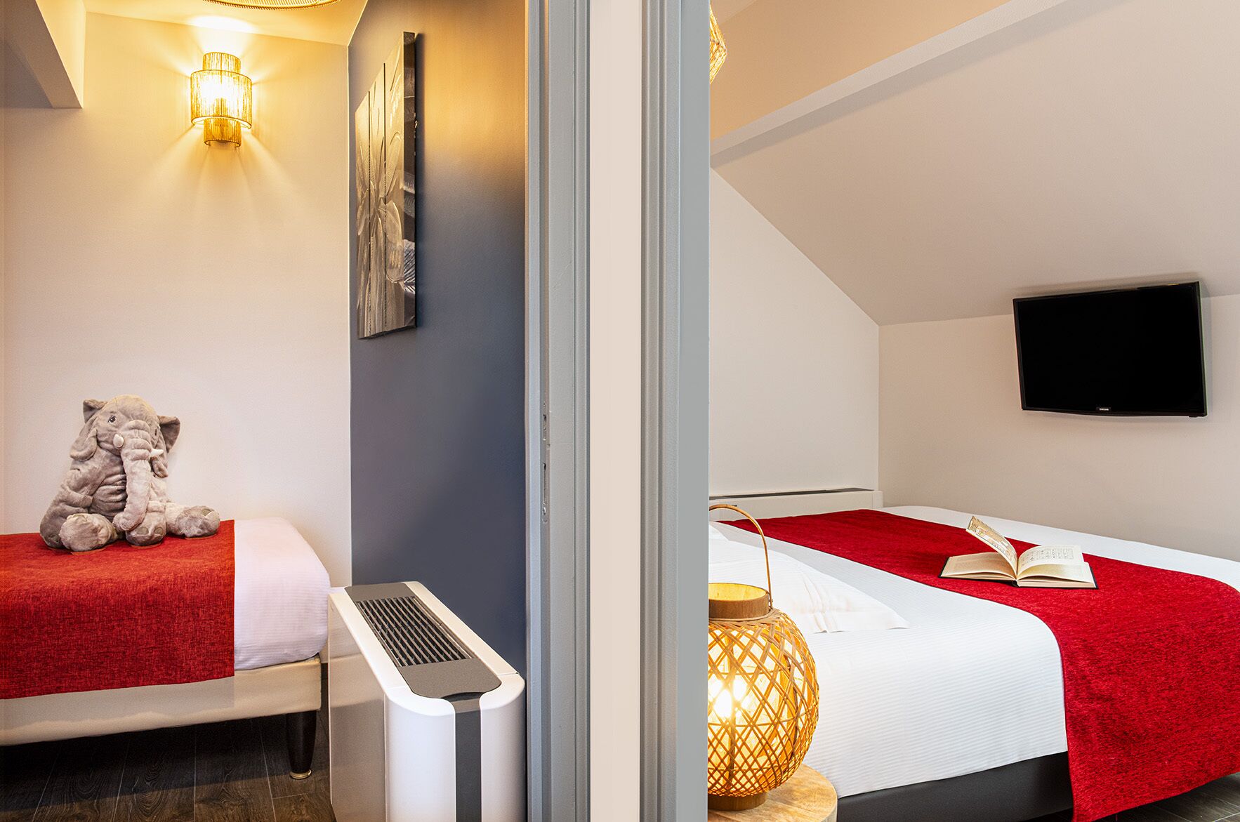 Una habitación de hotel con cama, calefacción, televisor de pared y un peluche de elefante.