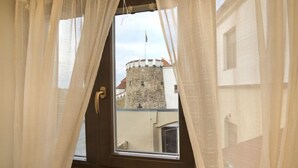 A room with a window featuring a view of a stone tower. - U Zlateho byka (Pisek)