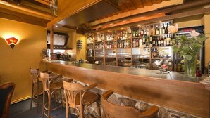 A bar area with wooden chairs, a counter with bottles, and a stone wall. - U Zlateho byka (Pisek)