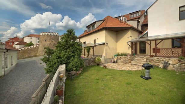 A residential area with stone walls, a grassy lawn, and a small tree. - U Zlateho byka (Pisek)