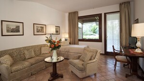 A living room with a sofa, armchair, and a small table with a vase of flowers. There are two lamps, a TV, and a window with curtains. - Villa Dacri (Venice)