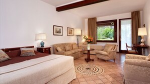 A hotel room with a bed, a sofa, a chair, a small table, and a window with curtains. - Villa Dacri (Venice)