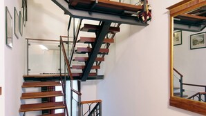 A multi-level wooden staircase with glass railings and a patterned rug at the bottom. - Villa Dacri (Venice)