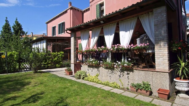 A pink building with a covered patio area, stone steps, and potted plants. - Villa Dacri (Venice)