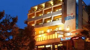 Un hotel de varios pisos con un balcón en el segundo nivel, un cartel que dice 