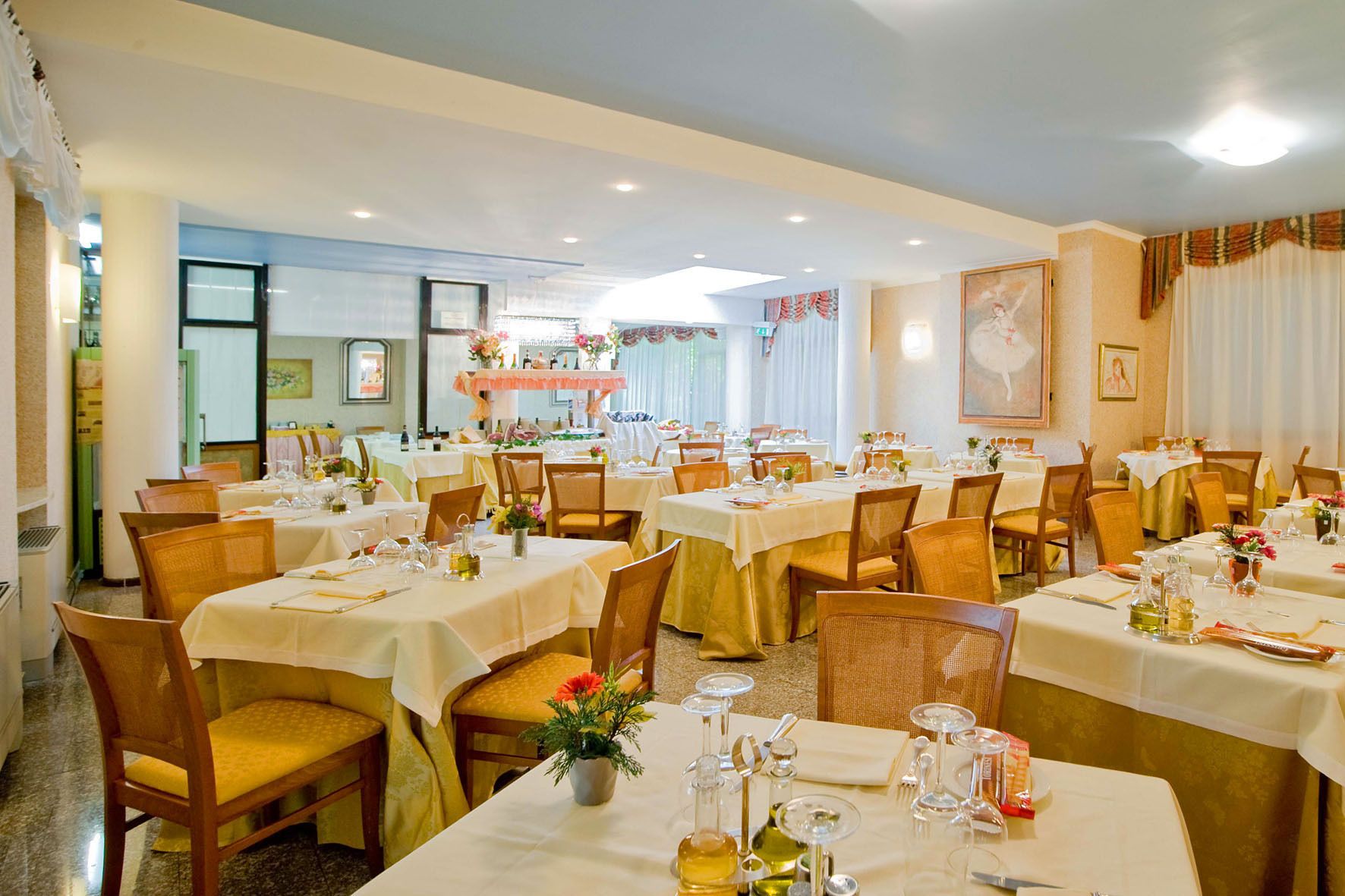 A dining area with multiple tables set for service, featuring chairs and table settings.