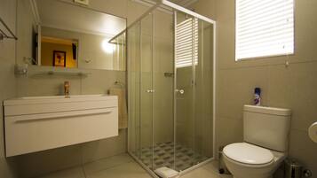 Een badkamer met een douche met glazen wand, een toilet en een wastafel met spiegel.