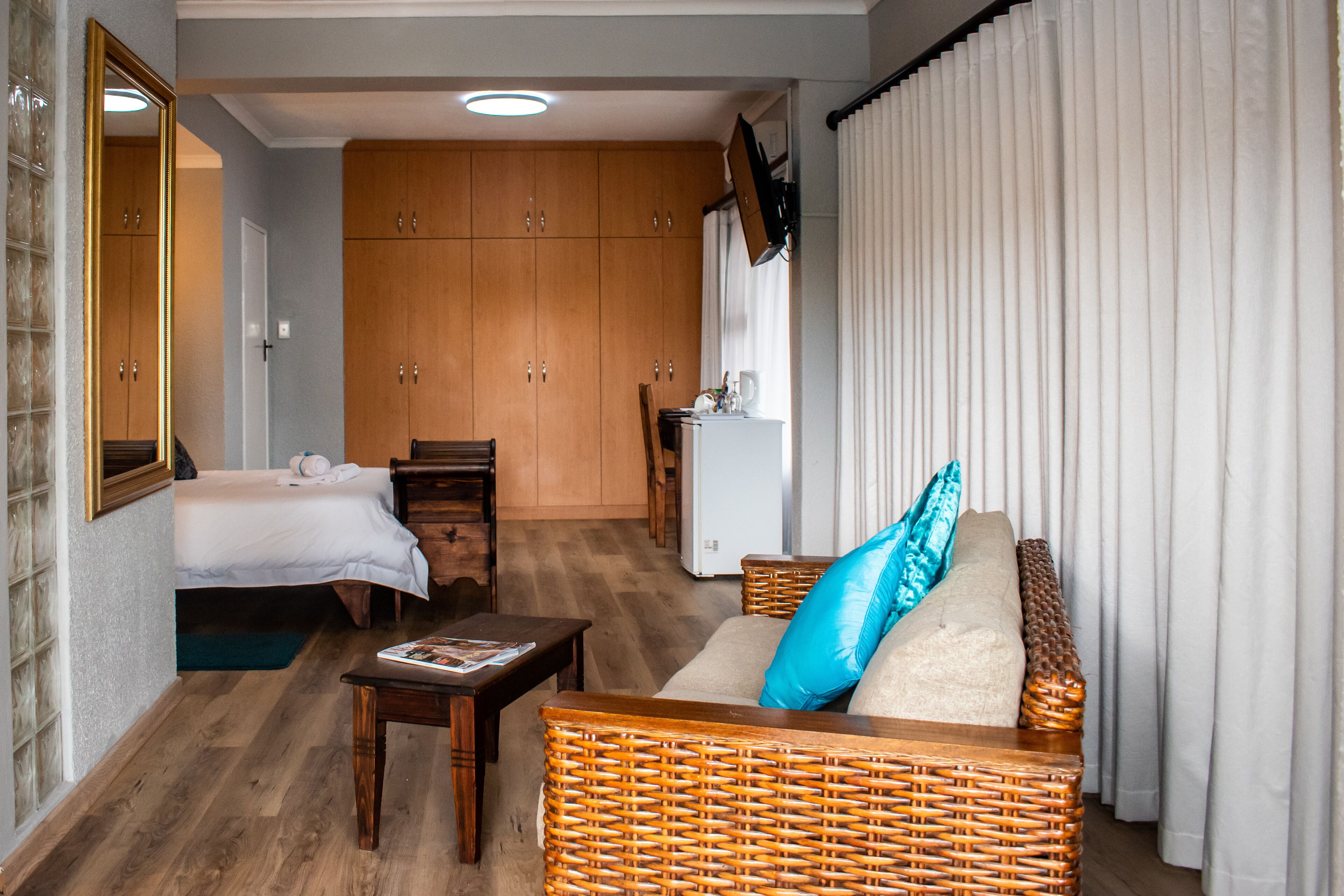 A hotel room with a bed, a sofa, a small table, and a kitchenette.