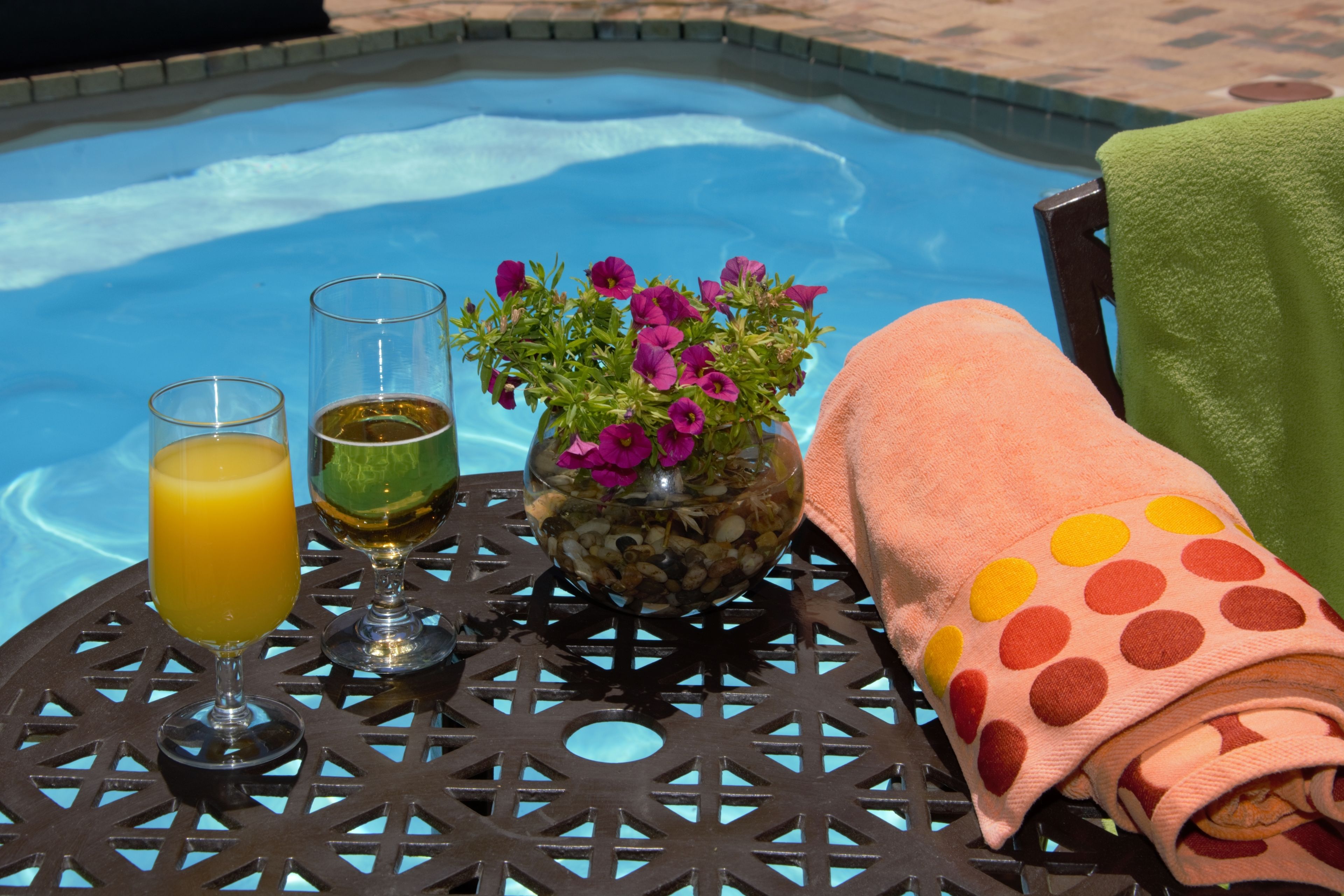 Een tafel met twee glazen drankjes, een bloevas en een handdoek.