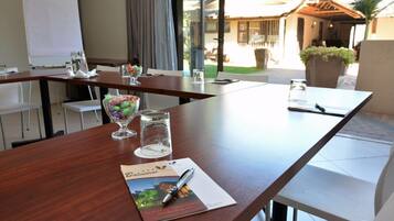 A conference table with a glass bowl of candies, a glass of water, and a pen on a brochure.