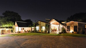 Un hotel con camino de ladrillo, varias construcciones e iluminación exterior.