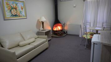 A living room with a sofa, a table with chairs, a fireplace, and an air conditioning unit.