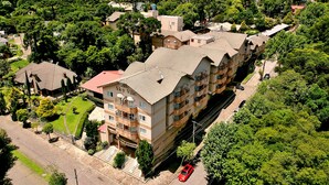 Hotel com vários andares e um pátio central, rodeado por vegetação exuberante e uma paisagem acidentada.