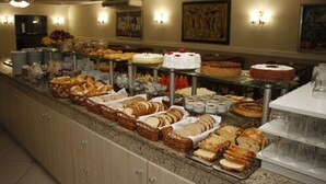 Buffet com diversos pães, doces e bolos.