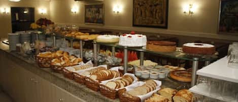 A buffet with various breads, pastries, and cakes.