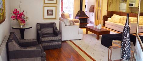 A living room with a sofa, armchairs, a coffee table, and a fireplace.