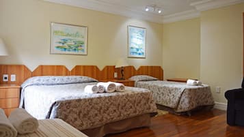 A hotel room with two beds, wooden headboards, and artwork on the walls.