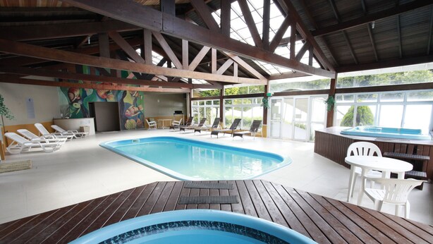 Uma área de piscina interna com espreguiçadeiras e uma banheira de hidromassagem.