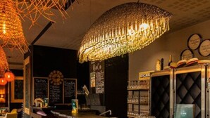 A bar area with a counter, stools, and a decorative hanging light fixture. - Safari Hotel (Carpentras)