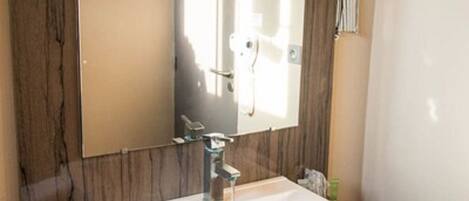 Un baño con un espejo grande, un lavamanos blanco y un mueble de tocador de madera.
