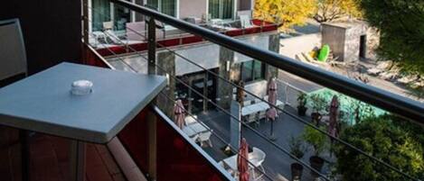 Un balcon avec une table et des chaises, donnant sur un immeuble à plusieurs étages, lui-même doté de balcons.
