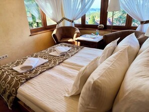 A hotel room with a bed, a chair, a table, and a view of the outdoors. - Dwór Karolówka (Zakopane)