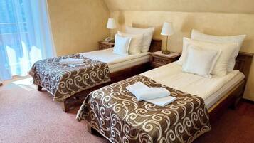 Two twin beds with patterned bedspreads, bedside lamps, and a window with curtains.