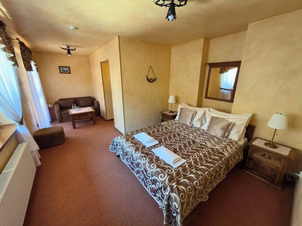 A hotel room with a bed, bedside tables, a desk, a chair, and a ceiling fan.
