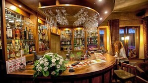 A bar area with shelves of liquor bottles, a wooden counter, and hanging glassware. - Dwór Karolówka (Zakopane)
