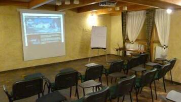 Un salón de conferencias con una pantalla de proyector, una pizarra y filas de sillas.