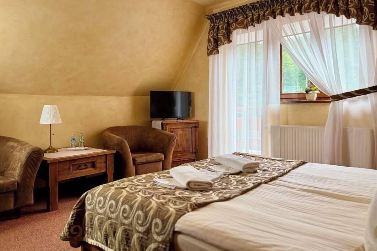 A hotel room with a bed, a desk, a chair, a television, and a window with curtains.