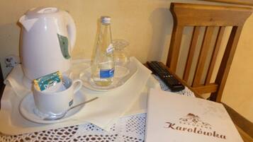 Une table avec une cafetière, une bouteille, une télécommande et une serviette de table ornée d’un logo.