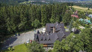 A large building with multiple roofs and a parking lot. - Dwór Karolówka (Zakopane)