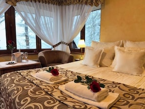 A hotel room with a large bed, a chair, a bedside table with a lamp, and a window with curtains. - Dwór Karolówka (Zakopane)