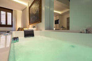 Une salle de bain moderne avec une grande baignoire, un miroir, un lavabo et un téléviseur.