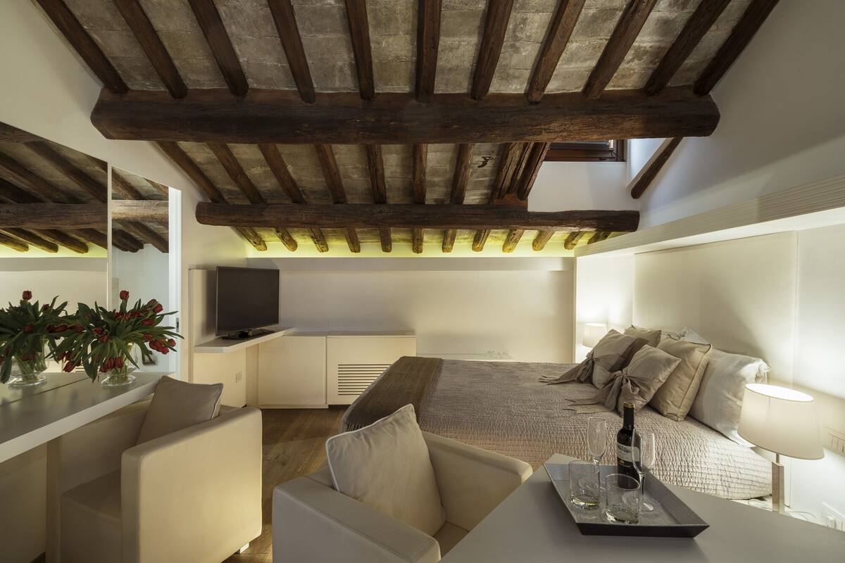 Una sala de estar moderna con techo alto, un sofá, un televisor y un comedor.