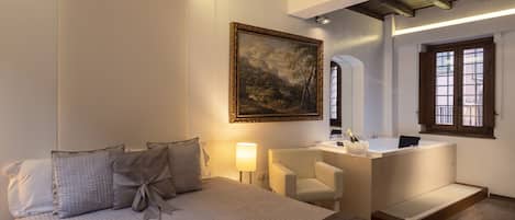 A hotel room with a bed, a desk, a chair, a large mirror, and a painting on the wall.