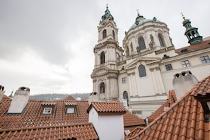 A historic building with a prominent bell tower and a dome, surrounded by terracotta-tiled rooftops. - Miss Sophie's Charles Bridge (Prague)