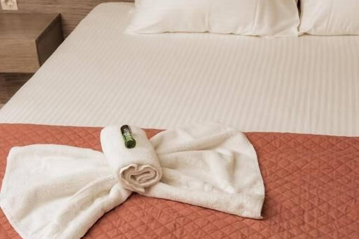 Una cama bien hecha con una toalla doblada y un objeto verde sobre ella.