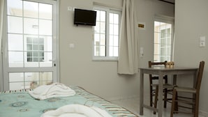 Una camera da letto con un letto, un tavolino, due sedie, una TV e una finestra con tende.