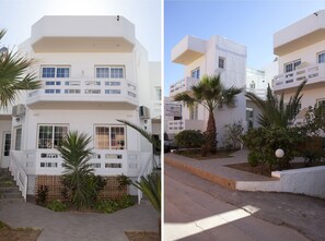 Ein modernes, mehrstöckiges Gebäude mit flacher Fassade, mehreren Balkonen und einem geschlossenem Eingangsbereich.